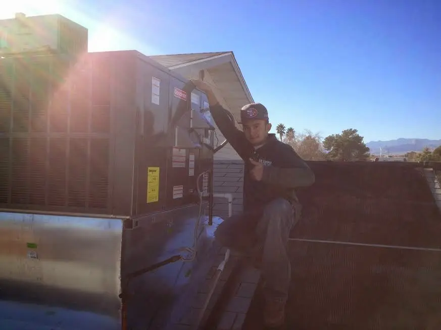 HVAC technician performing AC Tune-Up on a rooftop unit in Burton