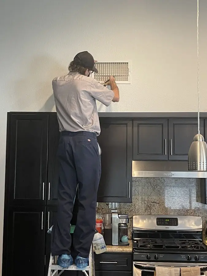 Technician inspecting an air vent during HVAC service in Burton
